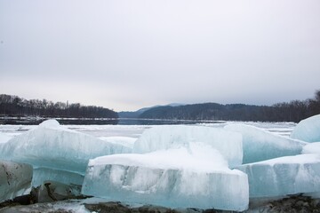 some big blue icebergs standing near the water and some snow