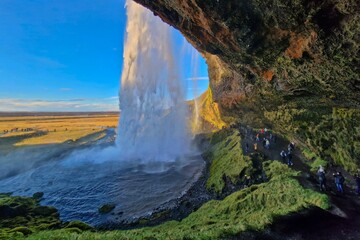 People admiring a majestic waterfall, standing on the side of a rocky cliff, Iceland, Reykjavik