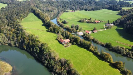 an aerial photo of the river in a green field next to houses