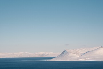 Scenic landscape of snow-covered mountains near a body of water in Svalbard
