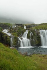 Vertical shot of flowing waterfalls on a cliff in Iceland