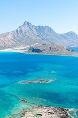Crystal-clear turquoise waters of Crete island in Greece with a rocky shoreline and hills