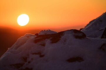 the sun rising in the background while it is snow covered