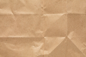 Detailed close-up of crumpled brown paper, with light casting shadows over the uneven surface,...