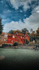 A vertical shot of a bright orange brick house with ivy plants in a rural countryside