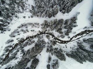 Aerial view of a tranquil winter landscape with a frozen river snaking through a snowy forest