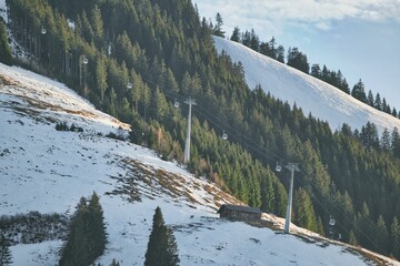 ski lifts are up a steep snowy hill near trees and mountains