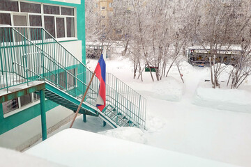 Russian flag snow above the entrance to the kindergarten building in winter.