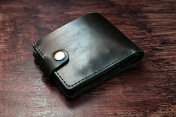 Men's wallet made of black leather on dark stylish wood..