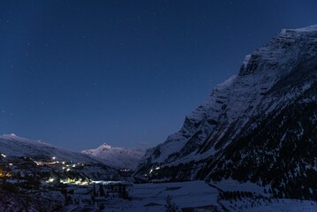 the night sky is lit up as a snow covered mountain is in the distance