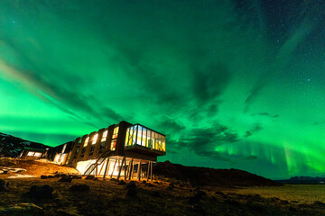 Aurora borealis, Northern lights glowing over luxury hotel on volcanic wilderness in winter at Iceland