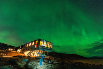 Aurora borealis, Northern lights glowing over luxury hotel and male tourist enjoying on mount Hengill in winter at Iceland - 773154560