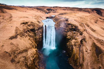 Aerial drone view of Majestic powerful Skogafoss waterfall flowing from cliff among brown mountain in autumn at Southern of Iceland - 773154918