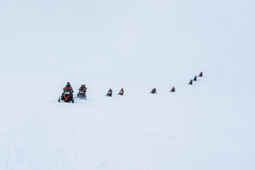 Group of tourists riding snowmobiles on snowy glacier mountain - obrazy, fototapety, plakaty