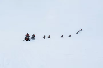 Fotobehang Group of tourists riding snowmobiles on snowy glacier mountain © Mumemories