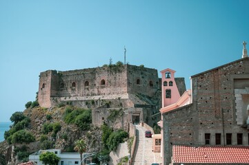 some buildings a car and mountains and a blue sky with clouds: Scilla, Calabria - obrazy, fototapety, plakaty