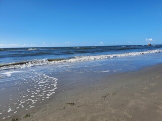 Foamy waves of the North Sea hitting the sandy beach in St. Peter-Ording