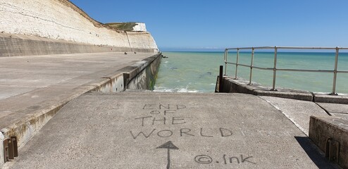 Text 'end of the world' on the ground in a harbor