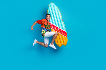 Full body photo of nice young man hold surfboard jump summer holiday isolated on blue color...