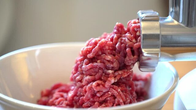 Minced meat in a meat grinder. Preparing fresh ground beef for cutlets in the kitchen.