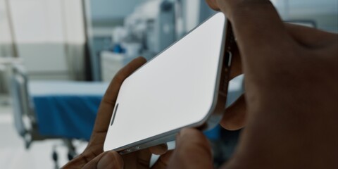 Black African-American male using smartphone with a blank screen in hospital