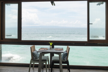 Elegant Seaside Dining Setup Featuring Wooden Tables and Ocean Views in a Tranquil Restaurant Atmosphere.