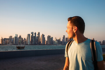Portrait of man looking back at urban skyline of Doha. Solo traveler in Qatar..