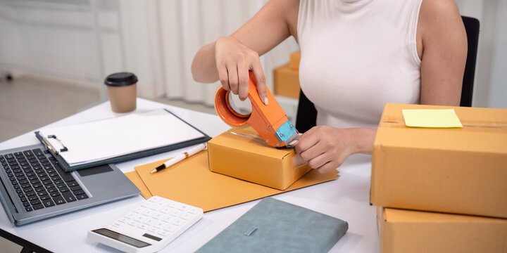 Woman asian use scotch tape to attach parcel boxes to prepare goods for the process of packaging, shipping, online sale internet marketing ecommerce concept startup business idea