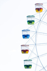 Close up view of a ferris wheel and its colorful cabins on a clear sky