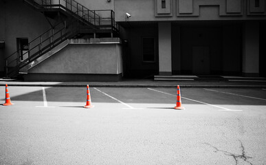 Black & white empty parking colored with orange cones backdrop