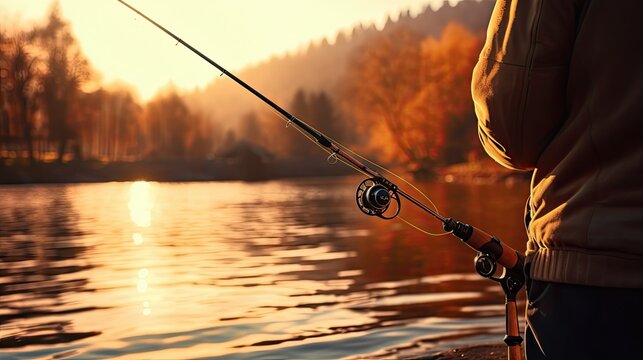 A man is fishing. A close-up of a fishing rod on the background of a lake, a beautiful sunset