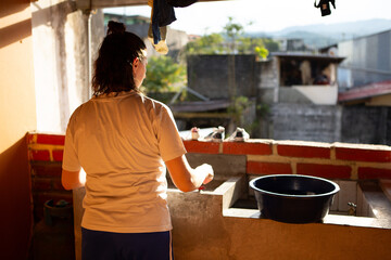 woman washing clothes by hand on a sunny rooftop