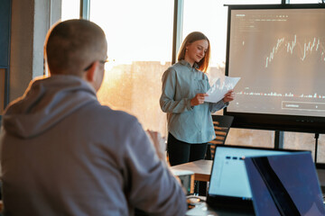 Guy is listening. Female business trainer is against projector with business data, teaching the man