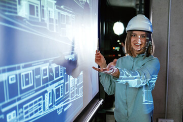 In white hard hat. Female architect is showing construction site plan for building on projector