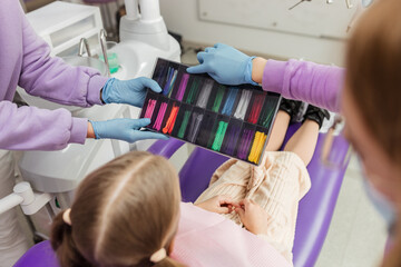 schoolgirl girl chooses the color of rubber bands for braces, pediatric dentistry
