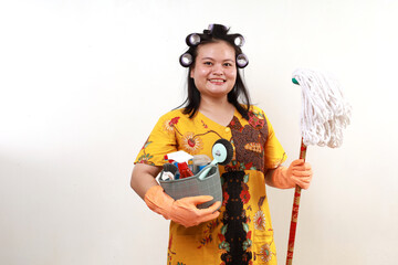 Happy cheerful asian housekeeper standing while holding home cleaning tools