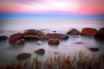 Rötlicher Sonnenuntergang mit Wassernebel am Ostseestrand