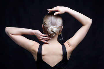 Female in black t-shirt with bun hairdo and hand near head. Back view portrait of young blonde woman. - 773201957