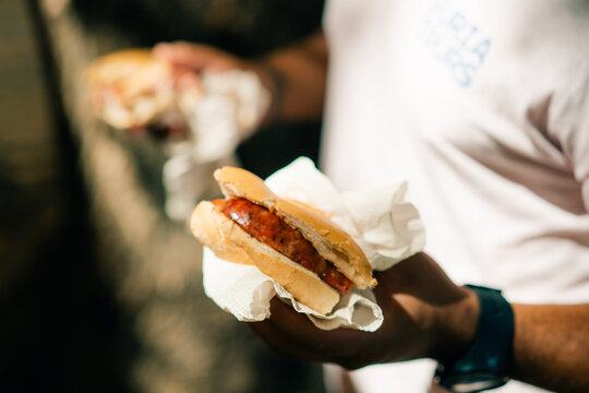 man eating traditional Argentine choripan sandwich at a street food market