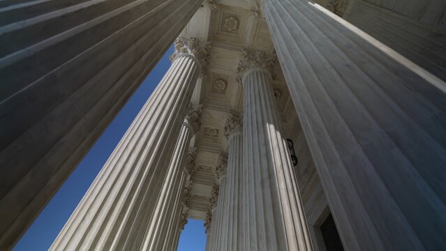 Very large towering columns in front of US Supreme Court building in Washington, DC showing judicial power over people and business.