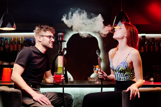 Young loving couple in the bar smoking hookah drinking cocktail