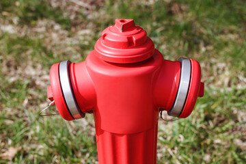 Red paint fire hydrant. Isolated on green grass. Fire department water supply for emergency. Brand new shiny vibrant red valve. Outdoor park emergency water supply.