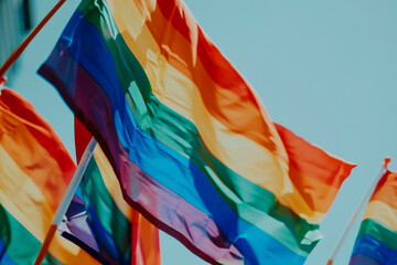Pride rainbow flags waving in the wind against a clear blue sky