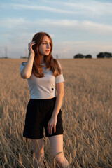 Naklejka na ściany i meble Young attractive red head woman in field at sunset 