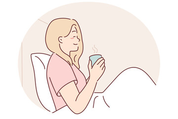 Woman is drinking coffee sitting in bed under blanket enjoying morning weekend and good mood