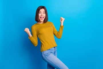 Fototapete Rund Photo of positive lucky lady dressed shirt yelling yes rising fists empty space isolated blue color background © deagreez