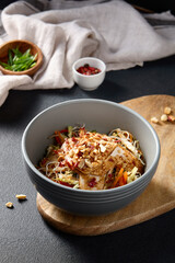 Salad with glass noodles, vegetables, and tofu with a nut dressing on a wooden stand