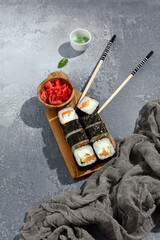 Maki sushi rolls with salmon, cucumber, and cream cheese, complemented by ginger and wasabi, ready for delivery