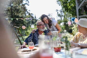 Mature granddaughter talking with grandparents, reunite after a long time. Family gathering at garden party. - obrazy, fototapety, plakaty