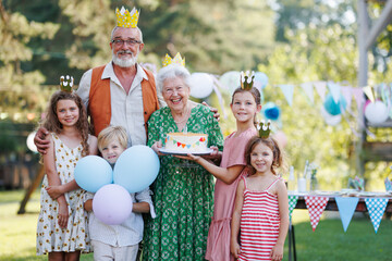 Garden birthday party for senior lady. Beautiful senior birthday woman holding cake and posing for...